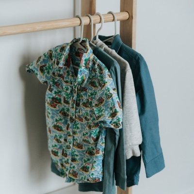 Roupas penduradas em estrutura de madeira com prateleiras brancas