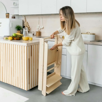 Mulher a montar escadote de madeira na cozinha moderna