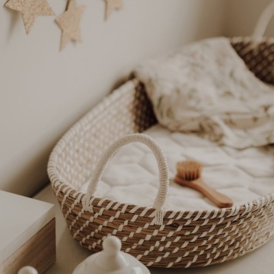 Berço em vime com colchão branco e decoração com estrelas de cortiça na parede