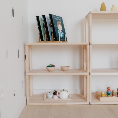 Prateleiras de madeira com brinquedos e livro infantil em ambiente branco