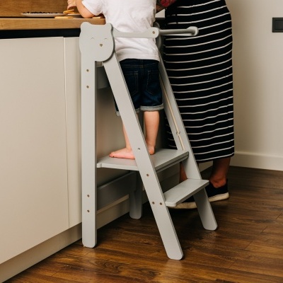 Escadote infantil branco de madeira numa cozinha com chão de madeira castanho