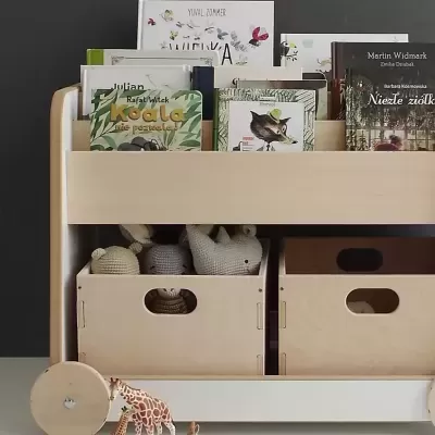 Carrinho de madeira clara com livros infantis e brinquedos em caixas de madeira