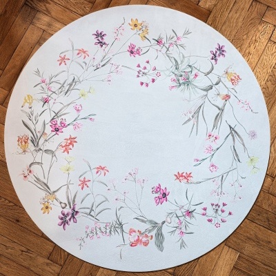 Tapete redondo branco com flores coloridas em chão de madeira
