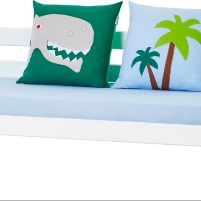 Cama infantil branca com colchão azul claro e duas almofadas coloridas com desenhos
