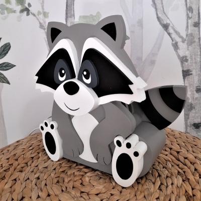 Figura decorativa de guaxinim cinza, branco e preto em MDF sobre superfície trançada