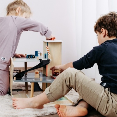 Crianças a brincar com parque de estacionamento de madeira com carros em tapete de pelúcia