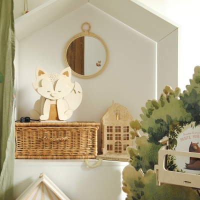 Estante branca com brinquedos de madeira, caixa de vime e espelho redondo com moldura de corda