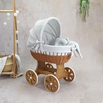 Berço de bebé em madeira e vime com tecido cinza claro em ambiente interior