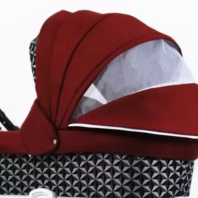 Carrinho de bebé vermelho com padrão geométrico preto e branco.
