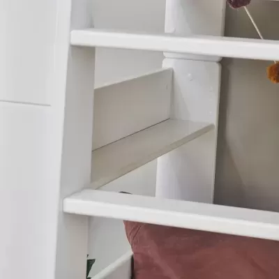 Cama alta branca em madeira com almofada castanha e parede cinzenta