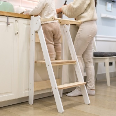 Bebé em escada branca a alcançar bancada de cozinha de madeira