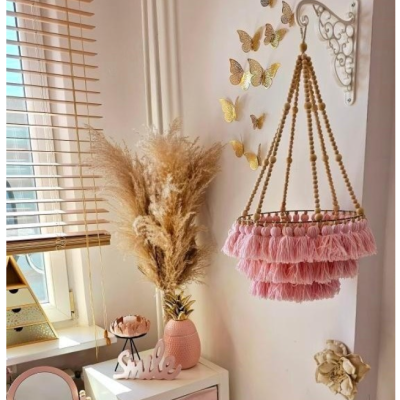 Candeeiro suspenso cor-de-rosa perto de jarra e borboletas douradas na parede