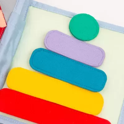 Brinquedo de tecido colorido com peças empilhadas em vermelho, amarelo, azul, lilás e verde.