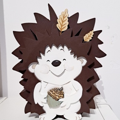 Figurinha decorativa de ouriço de madeira com folhas e bolota.
