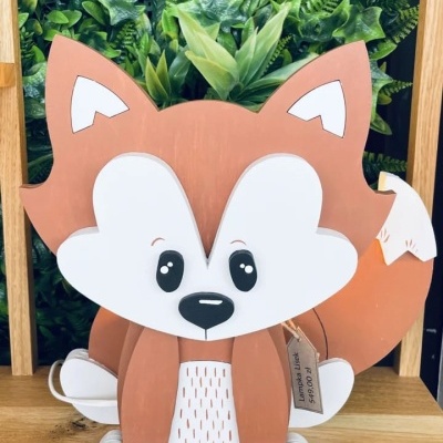 Boneco de raposa decorativo em madeira pintada com fundo de plantas verdes