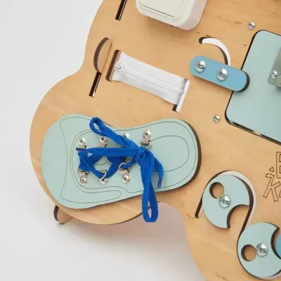 Painel de atividades em madeira com ténis azul claro e atacadores azuis para aprender a atar