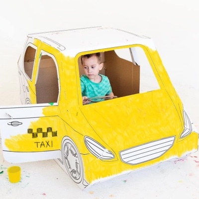 Brinquedo de carro táxi de cartão amarelo com criança dentro