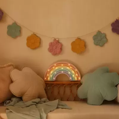 Decoração interior com almofadas florais, manta verde, guirlanda de flores coloridas e luz em forma de arco-íris LED