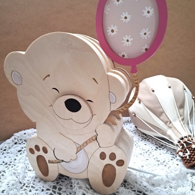 Figura decorativa de urso em madeira segurando balão cor-de-rosa com flores brancas