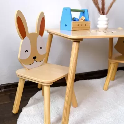 Conjunto infantil de madeira com cadeira em forma de coelho e mesa quadrada com brinquedos em cima