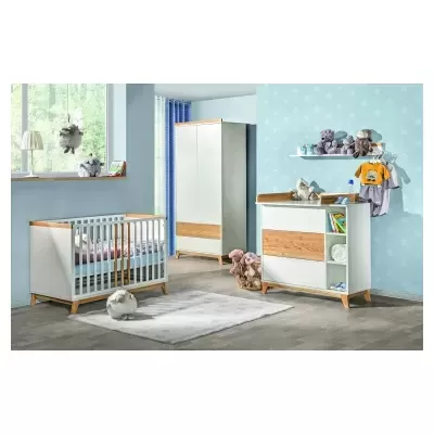 Quarto de bebé com móveis em madeira clara e branco, berço, cómoda e guarda-roupa, decorado com peluches e roupa de bebé, parede azul com estrelas.