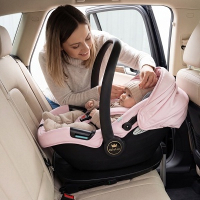 Cadeira auto para bebé rosa e preto com bebé e mãe no banco traseiro de carro bege