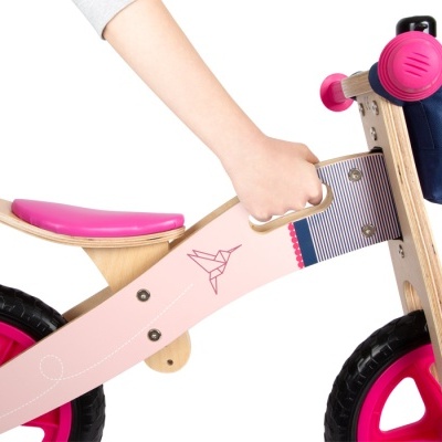 Bicicleta infantil de madeira com rodas rosa e bolsa azul no guiador