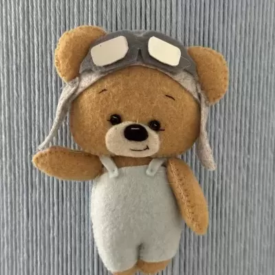 Urso de peluche castanho com fato branco e chapéu cinzento com óculos