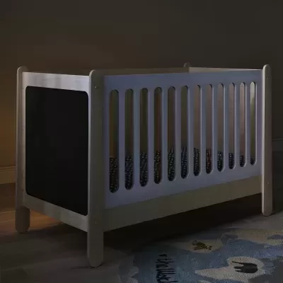 Berço de madeira clara com laca branca, panelas pretas, tapete azul no chão