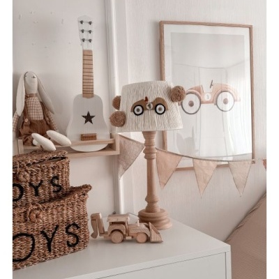 Quarto infantil com decoração incluindo cestos de palha, guitarra branca, candeeiro com abajur decorado com carro, brinquedo de madeira e quadro com ilustração de carro.