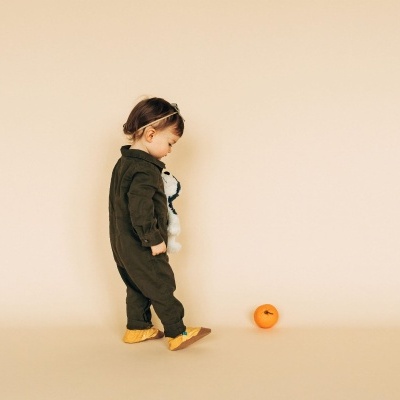 Criança pequena com fato verde e ursinho de pelúcia segurado