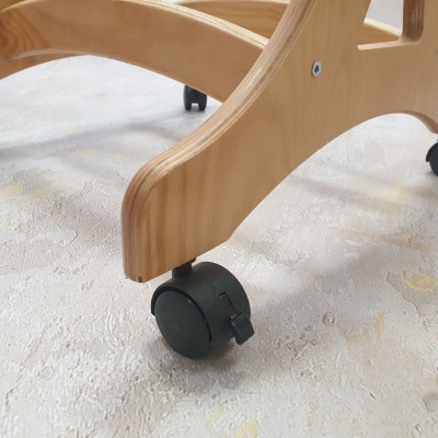 Base de madeira clara com rodas pretas sobre piso claro texturizado