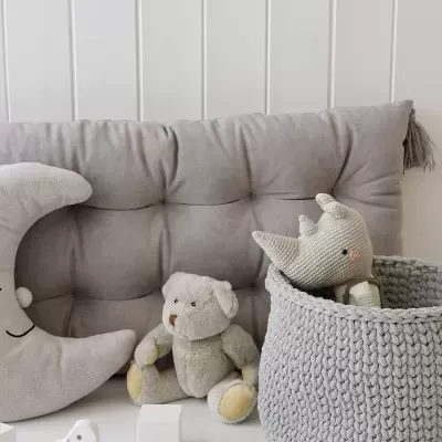 Brinquedos de pelúcia e cesta tricotada em tom cinzento sobre superfície branca