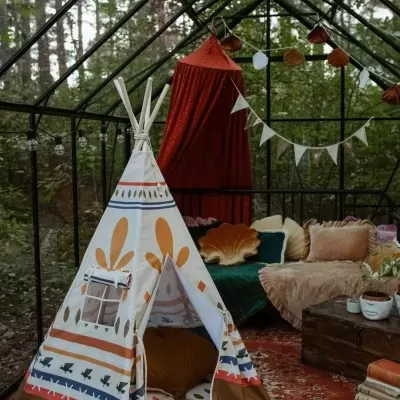 Tenda tipi infantil branca com estampas coloridas numa sala de vidro com decoração acolhedora