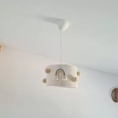 Candeeiro de teto branco com aplique de arco-íris e pompons em ambiente branco.