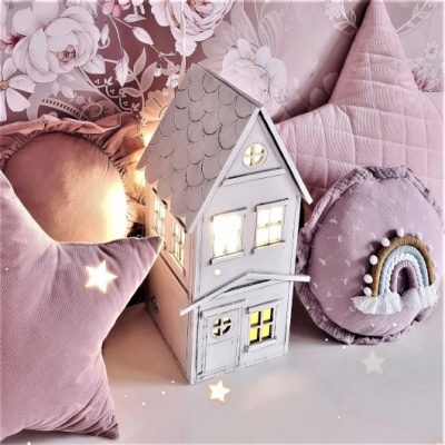 Casa decorativa branca iluminada entre almofadas cor-de-rosa
