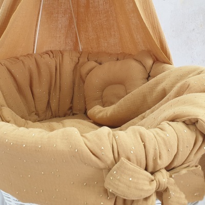 Berço de bebé com roupa de cama mostarda e mosquiteiro