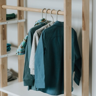 Estrutura de madeira clara com prateleiras brancas e camisas penduradas