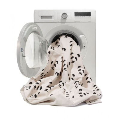 Máquina de lavar roupa branca com porta aberta e tecido bege com padrão de pandas