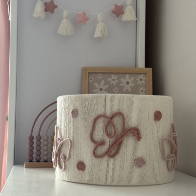 Luminária branca com bordados rosa em parede cinzenta e decoração infantil