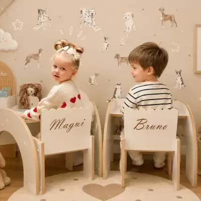 Crianças sentadas em cadeiras de madeira personalizadas numa sala infantil com decoração de cães e brinquedos macios