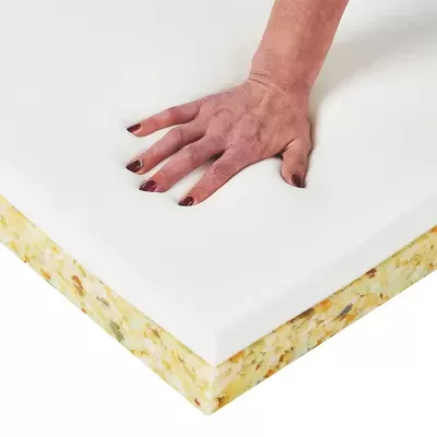 Colchão de espuma branca com camada inferior amarela e mão pressionando a camada superior.
