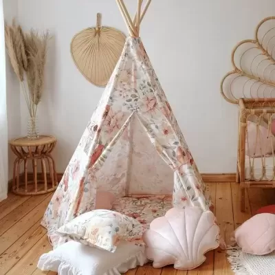 Tenda tipi infantil floral com almofadas decorativas num quarto claro