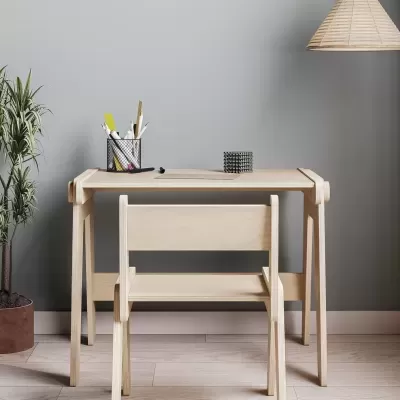 Conjunto de secretária e cadeira em madeira clara com acessórios de escritório e planta