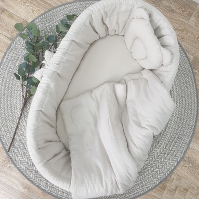 Cama de bebé cinza claro com rede cinza circular e ramo de folhas verdes