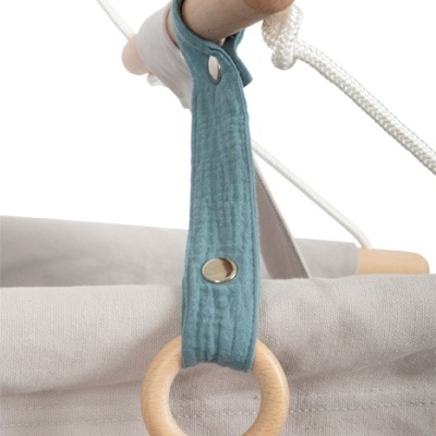 Detalhe de peça de cadeira suspensa infantil em tecido cinzento claro com suporte de madeira e alça azul com anel de madeira