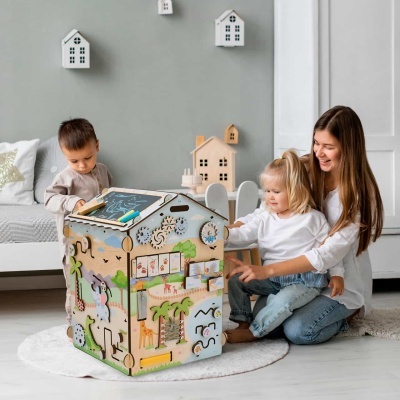 Casa de atividades infantil de madeira colorida com elementos educativos num ambiente de sala clara