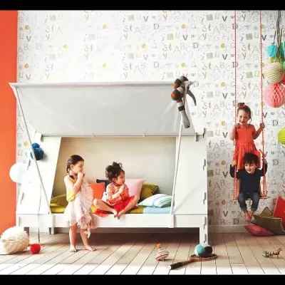 Quarto infantil com cama branca tipo cabana e baloiço interior com crianças a brincar