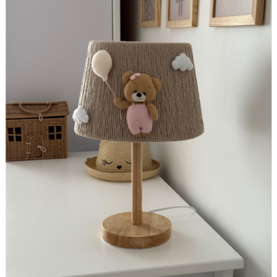 Candeeiro de mesa em madeira clara com abajur bege decorado com urso de peluche e balão.