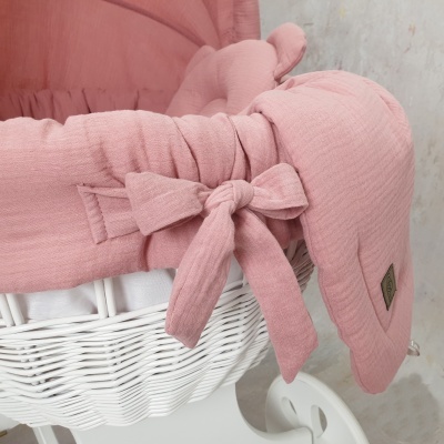 Berço branco em vime com forro rosa e laço de tecido ao lado